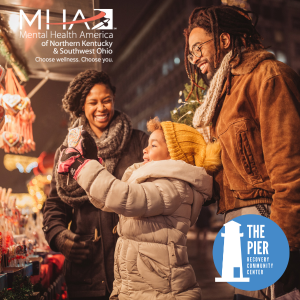 image of smiling family wearing winter clothes. They are looking at a holiday display of lights.