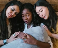 image of three women who are sad and hugging each other